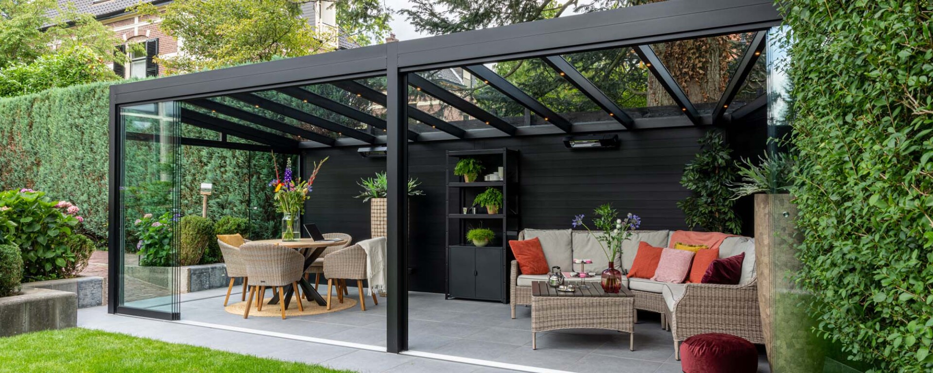 Verasol Profiline veranda met glazen schuifwanden en luxe ingerichte zithoek in de tuin