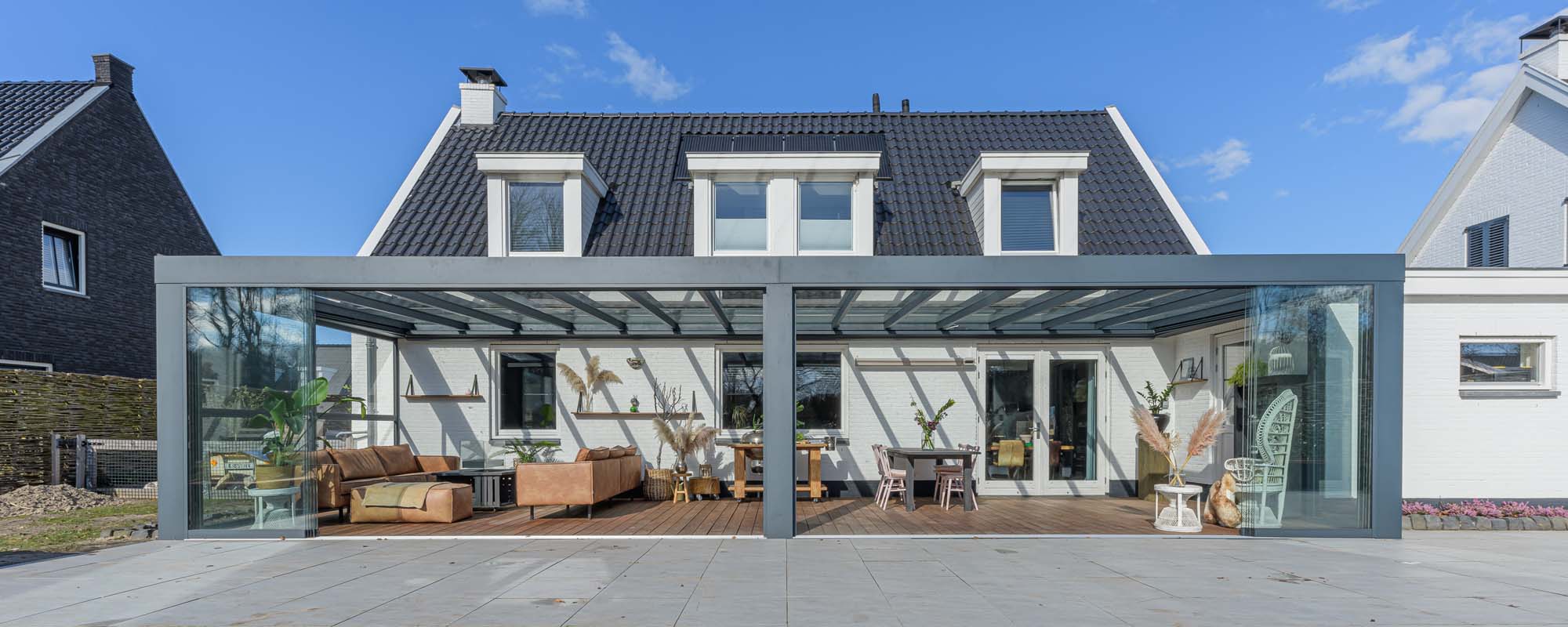 Verasol Cube veranda over de volledige breedte van een moderne woning, met glazen schuifwanden en sfeervol ingerichte zit- en eethoek.